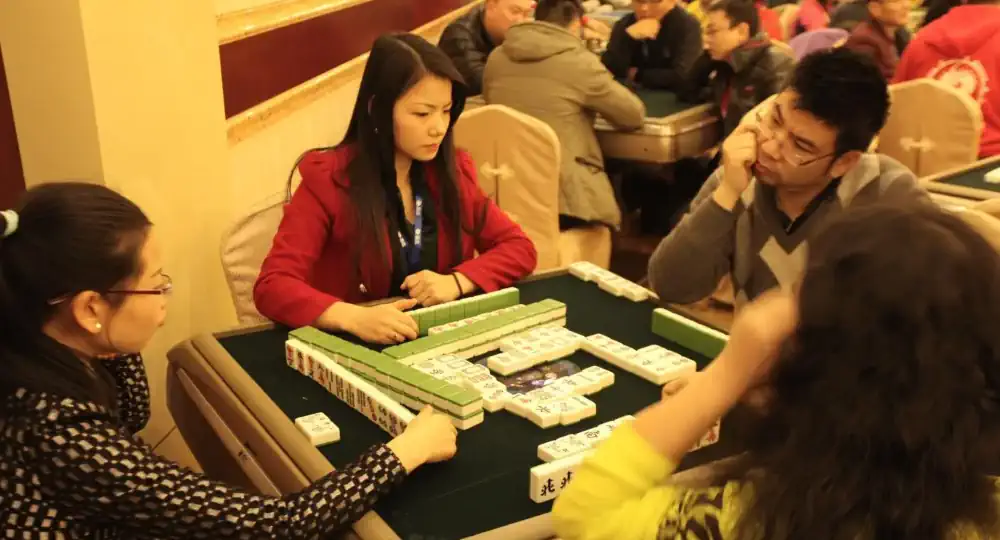 Žmonės, žaidžiantys tradicinį „Mahjong“
